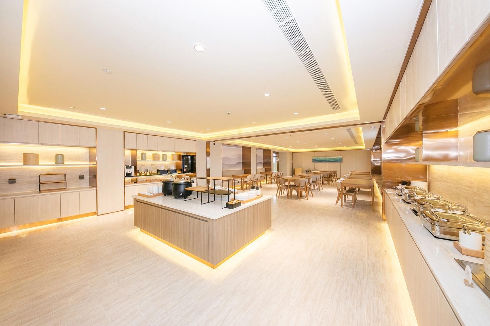 A modern hotel lobby with a central island, seating area, and a kitchen counter.