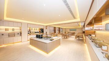 A modern hotel lobby with a central island, seating area, and a kitchen counter.