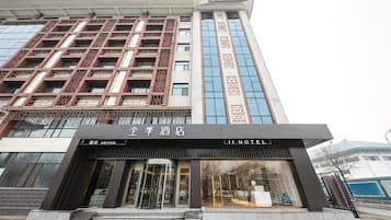 A hotel with a modern facade, featuring a prominent entrance with glass doors and a sign indicating it is the Ji Hotel.