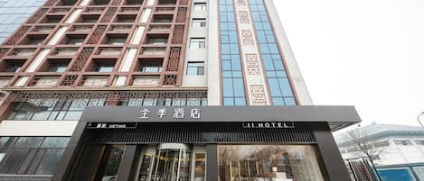 A hotel with a modern facade, featuring a prominent entrance with glass doors and a sign indicating it is the Ji Hotel.