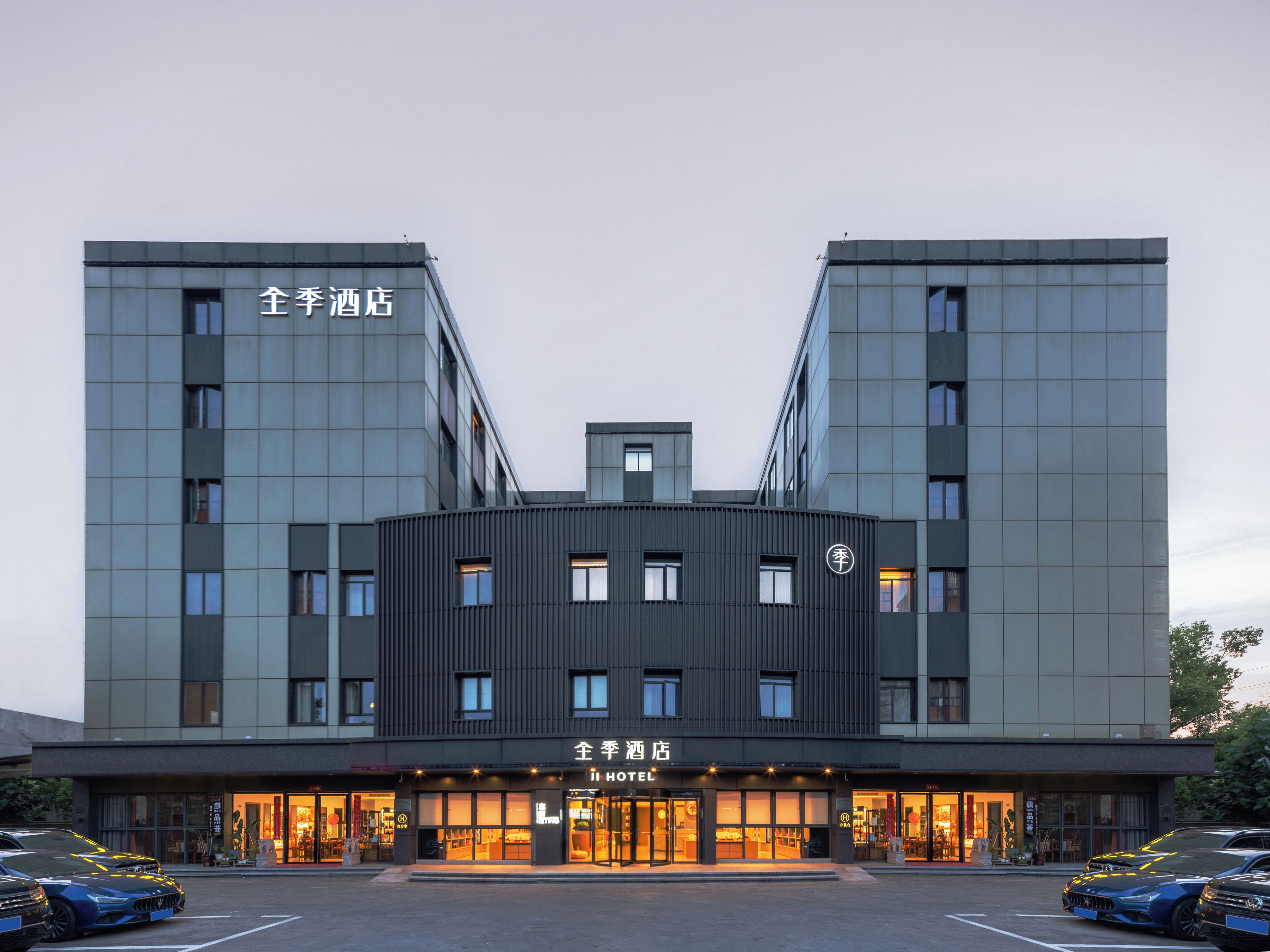 A hotel with a modern design, featuring a central entrance with a glass facade and multiple windows.
