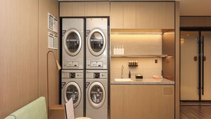 A modern laundry room with stacked washers and dryers, a sink, and a small table with a keyboard. - Ji Hotel (Nanchang)