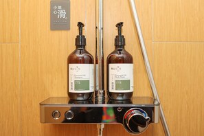 Two bottles of essential oil products on a metallic dispenser in a wooden room. - Ji Hotel (Nanchang)