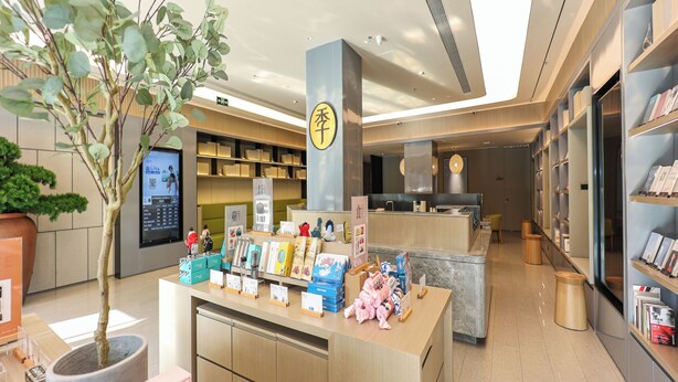 A modern bookstore interior with a central counter, shelves with books, and a decorative plant. - Ji Hotel (Nanchang)