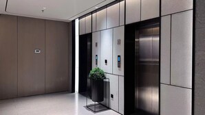 A modern elevator with a digital display, a potted plant, and a metallic finish wall. - Ji Hotel (Nanchang)