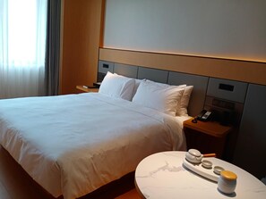 A hotel room with a large bed, bedside tables, a bedside phone, and a small table with a tray. - Ji Hotel (Nanchang)