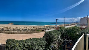 Vista sulla costa con spiaggia sabbiosa, cielo azzurro limpido e passeggiata lastricata.