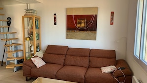 Un soggiorno con un divano marrone, un mobile in legno con vetrate e un quadro appeso al muro.