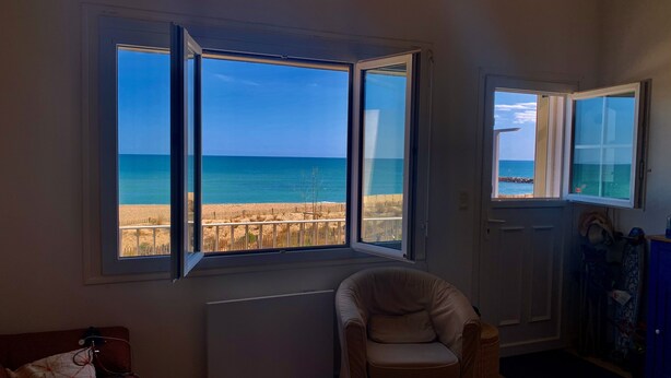 Una stanza con un'ampia finestra vista spiaggia e mare.
