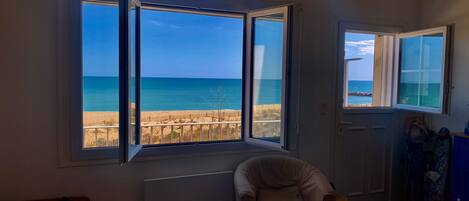 A room with a large window offering a view of the beach and ocean.