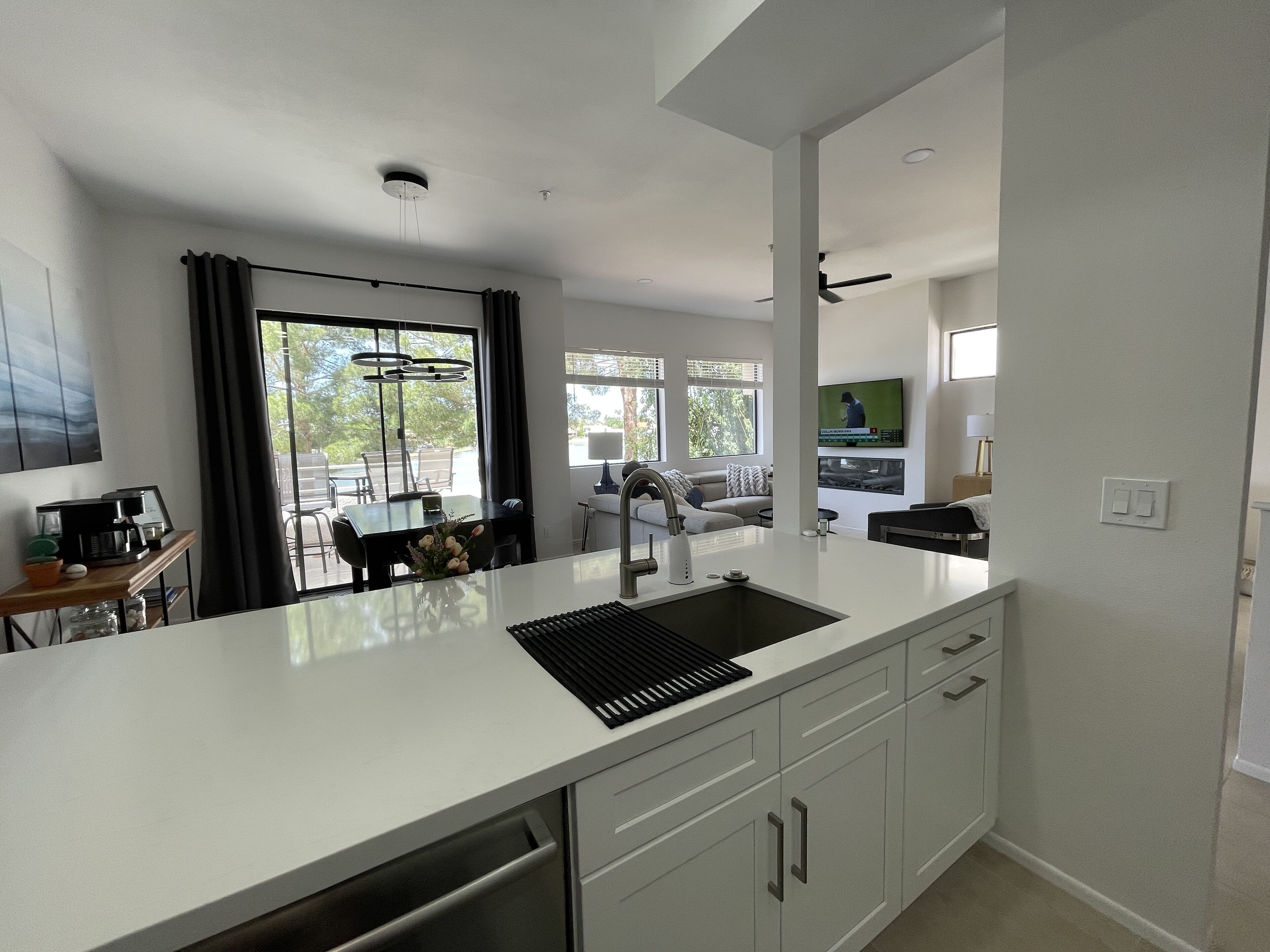 A modern kitchen with white cabinetry, a black countertop, and a built-in dishwasher.