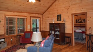 A wooden cabin interior with a red sofa, blue couch, and a ceiling fan. - Cozy Cabin for 4 with 2 King beds, 2 full baths, 2 fireplaces and upscale Decor! (Morganton)
