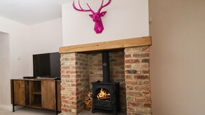 Una sala de estar con chimenea, un televisor sobre un soporte de madera y una decoración de cabeza de ciervo.