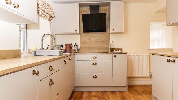 Una cocina moderna con armarios blancos, encimeras de madera y un horno empotrado.