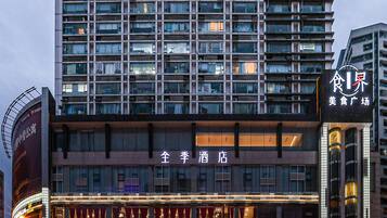 A hotel with multiple floors, a prominent sign for a hotel, and various storefronts including a Huawei store.