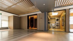 Een moderne hotellobby met een strak betegelde vloer en een plafond van houten latten.