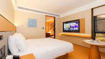 Habitación de hotel con cama, escritorio con teléfono, televisor montado en la pared y una mesita con una taza y una tetera.
