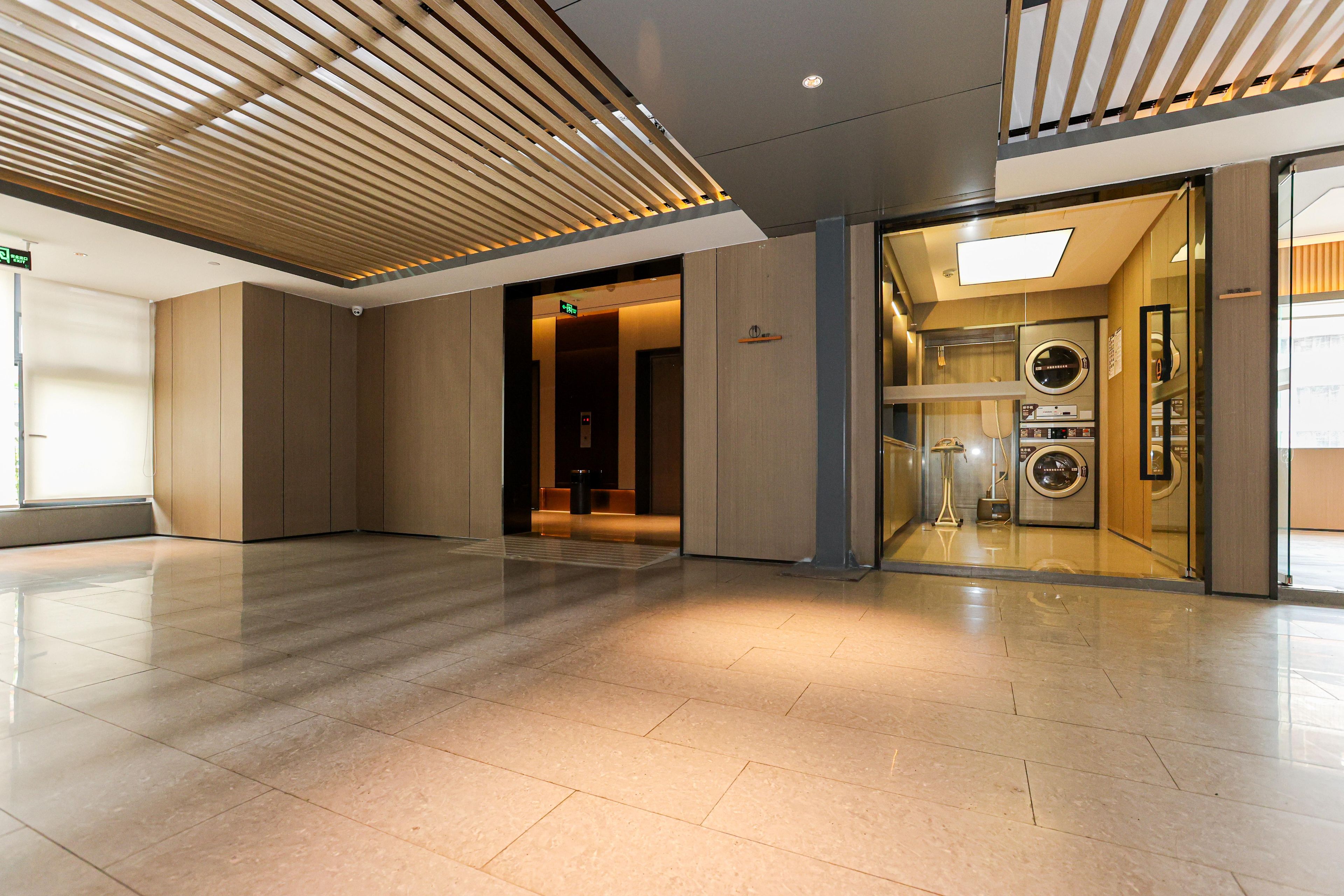 A modern hotel lobby with a clean, tiled floor and a wooden slatted ceiling.
