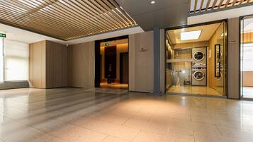 A modern hotel lobby with a clean, tiled floor and a wooden slatted ceiling.