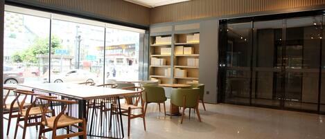 A modern library with a large window, wooden tables, and chairs.