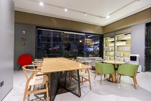 A modern interior with a wooden table and chairs, a red circular object, and a bookshelf. - Ji Hotel (Chengdu)