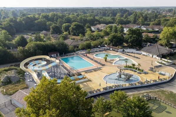Parque acuático con múltiples piscinas, toboganes y una fuente de agua serpenteante.