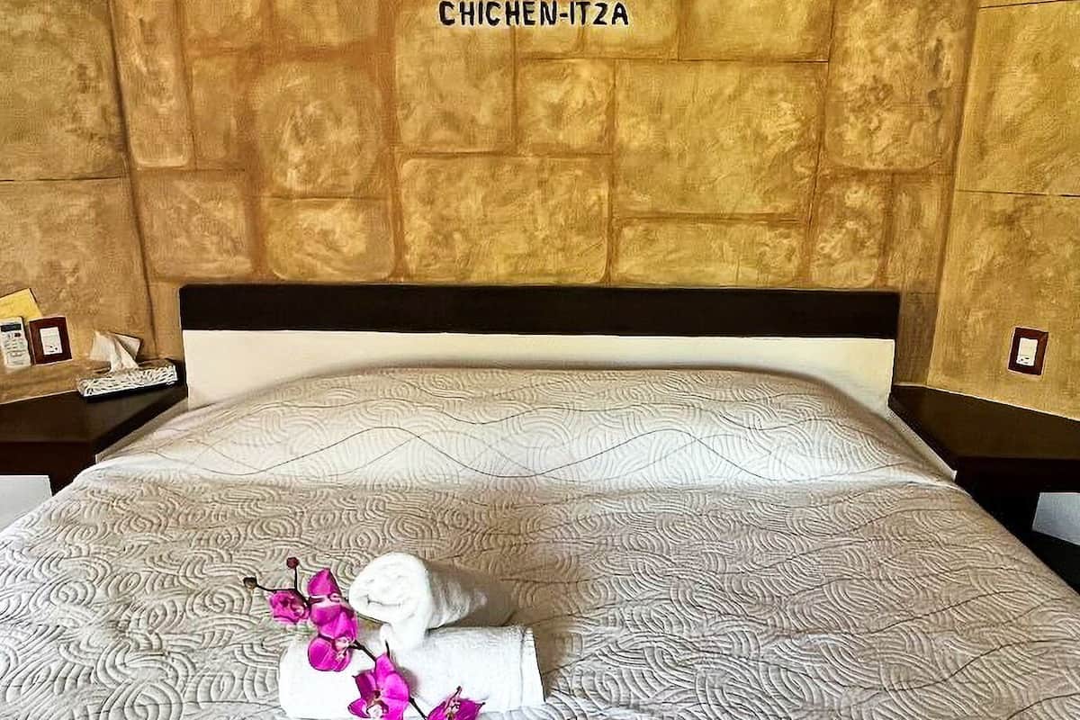 Una habitación de hotel con una cama, un adorno en la pared y una toalla con motivos florales.