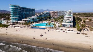A beachfront hotel with multiple buildings, a swimming pool, and a sandy beach. - Condo Aria Ocean 306 (Nuevo Nayarit)