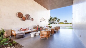 A modern outdoor lounge area with a sofa, chairs, and decorative items against a white wall. - Condo Aria Ocean 306 (Nuevo Nayarit)