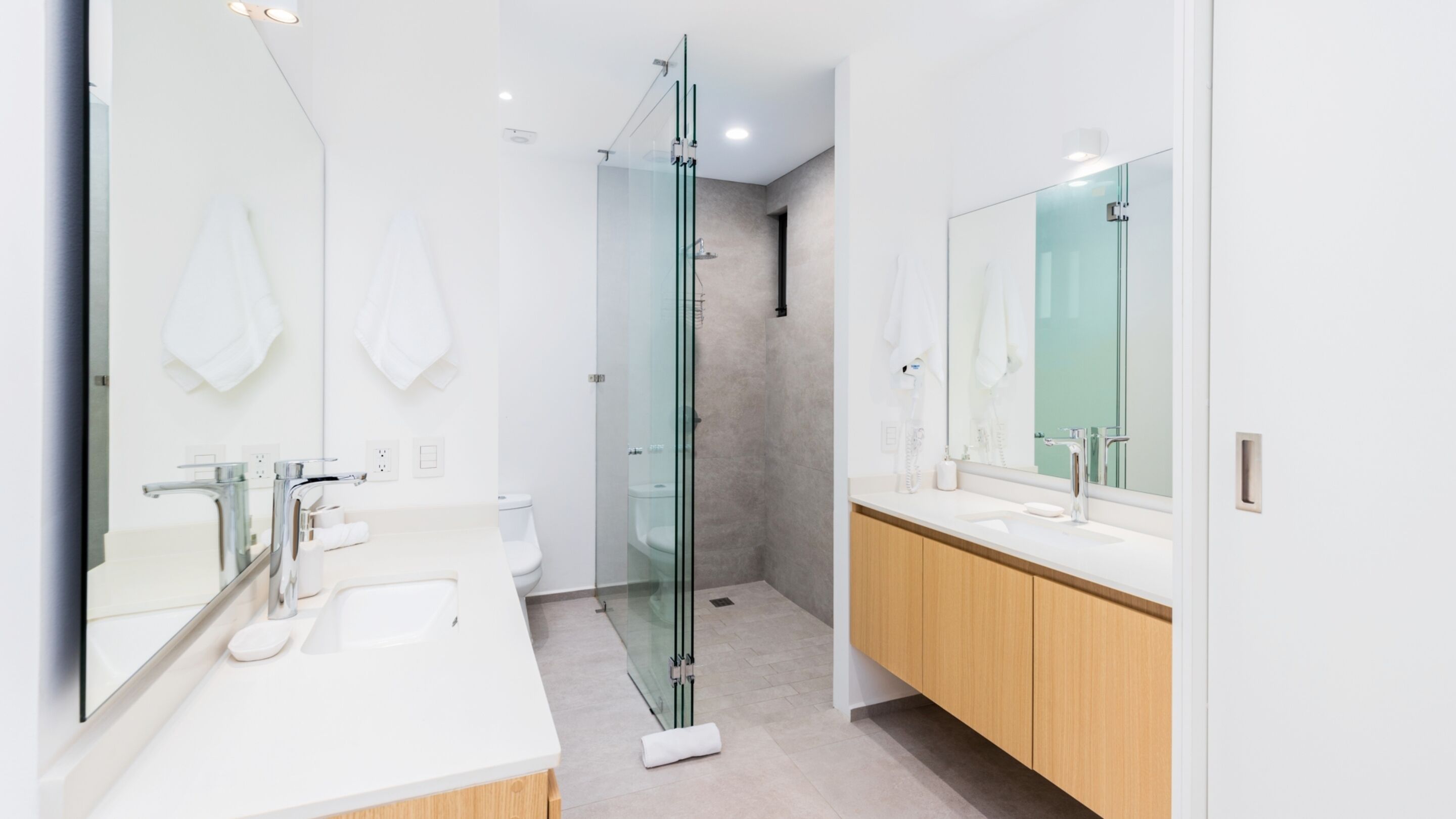 A modern bathroom with a glass shower enclosure, a double sink vanity, and a large mirror.