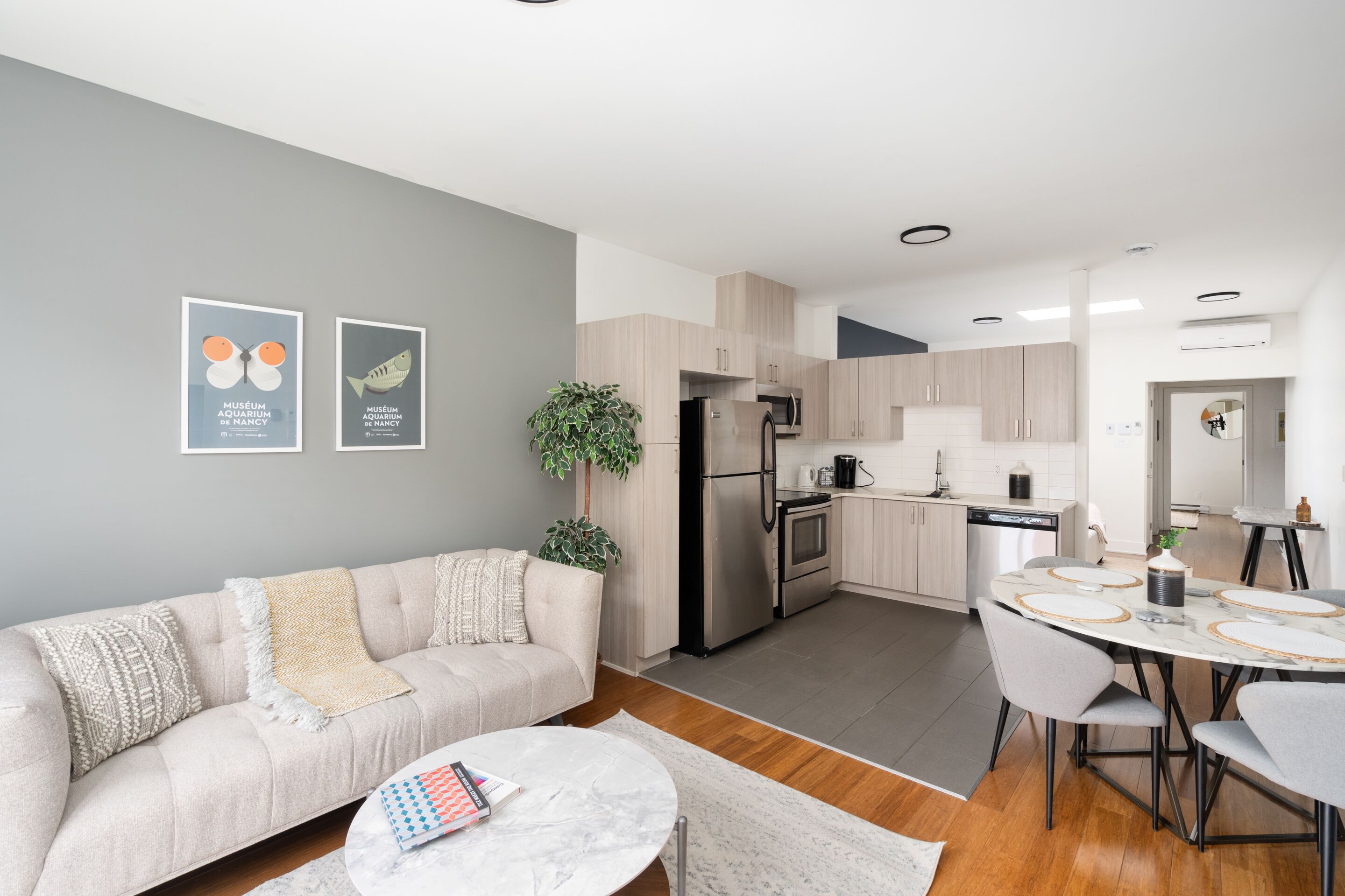 A modern kitchen with a dining area, featuring a sofa, a coffee table, and a dining table with chairs.