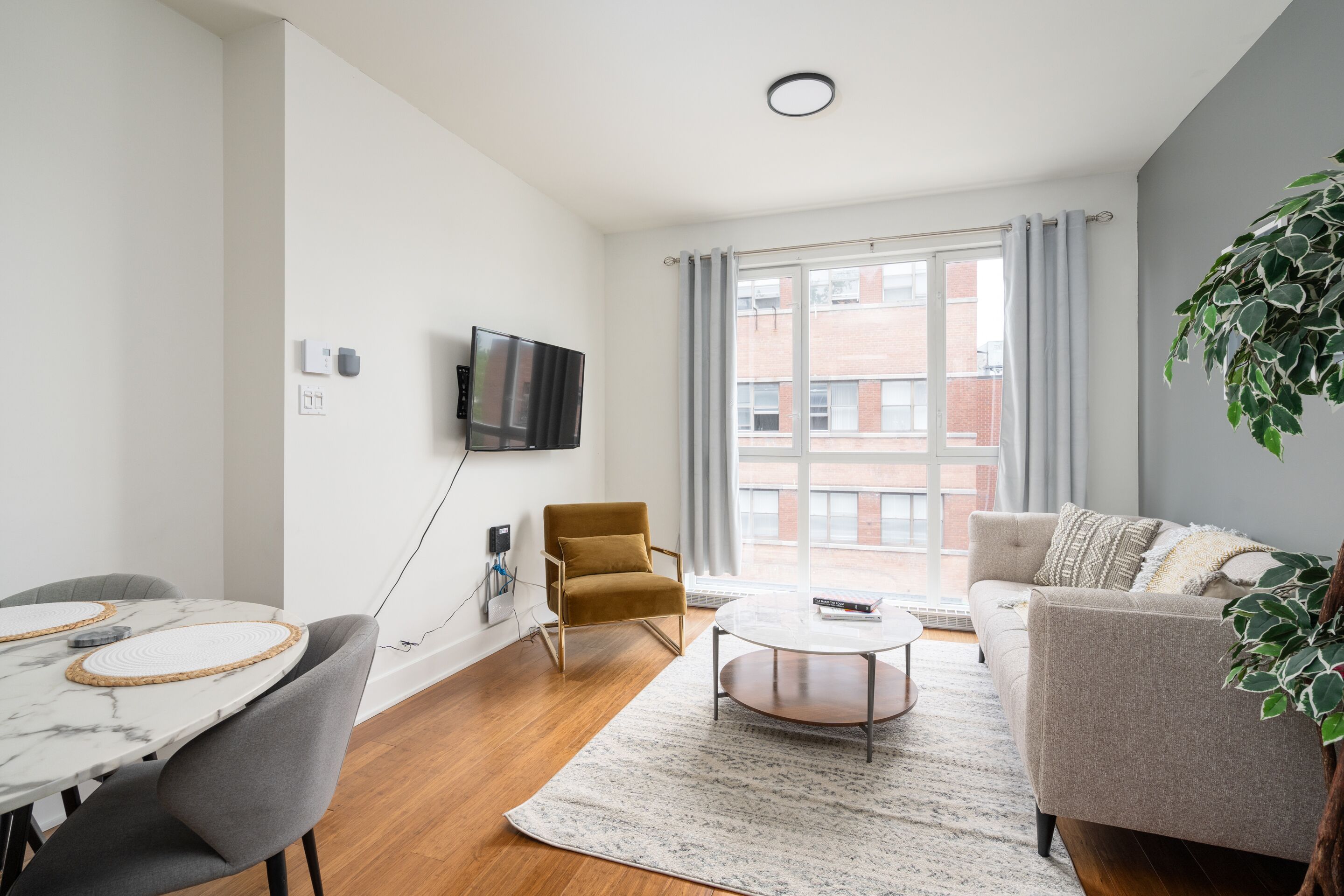 Una sala de estar moderna con un sofá, un sillón, una mesita de centro y un televisor montado en la pared.