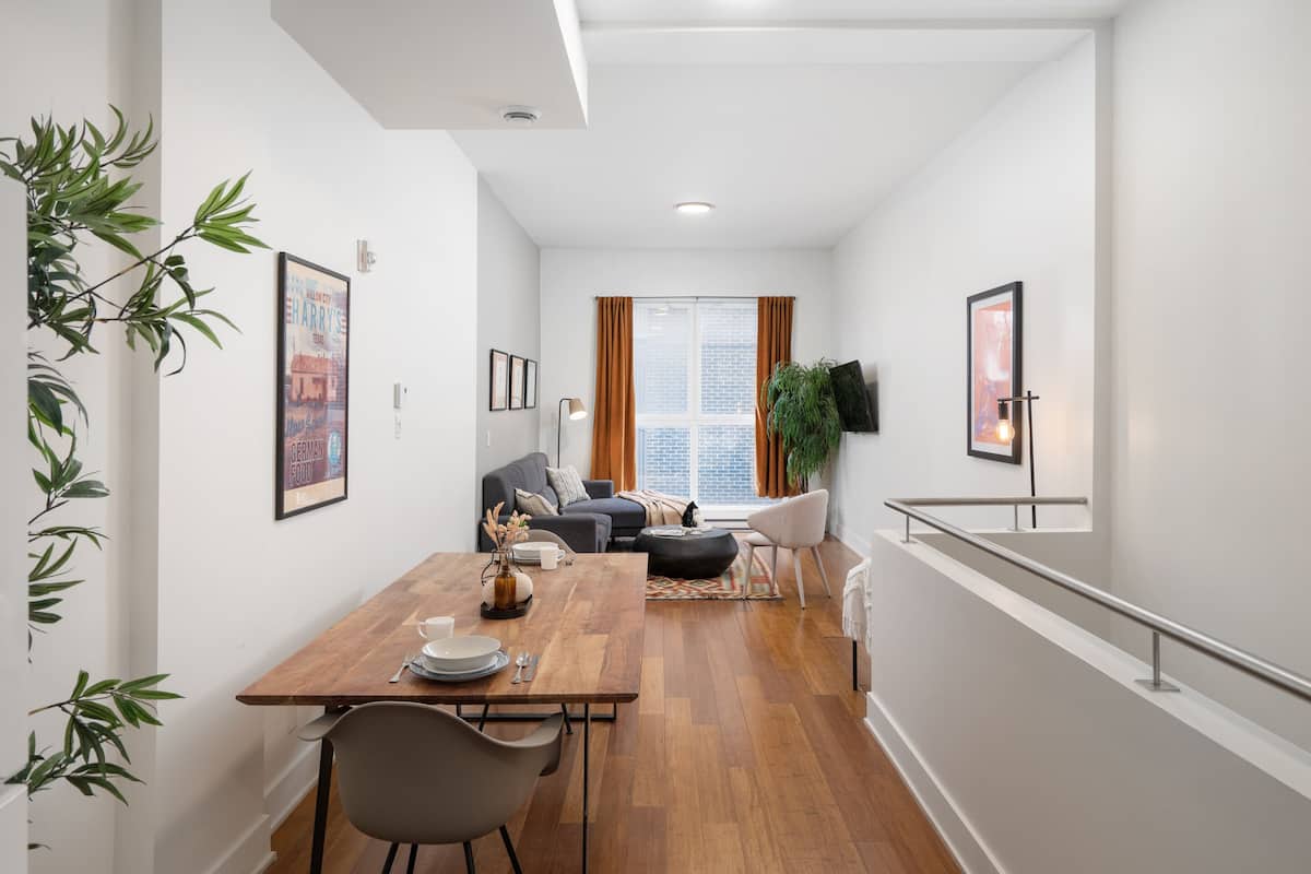 Un apartamento moderno con comedor, sala de estar y una escalera.