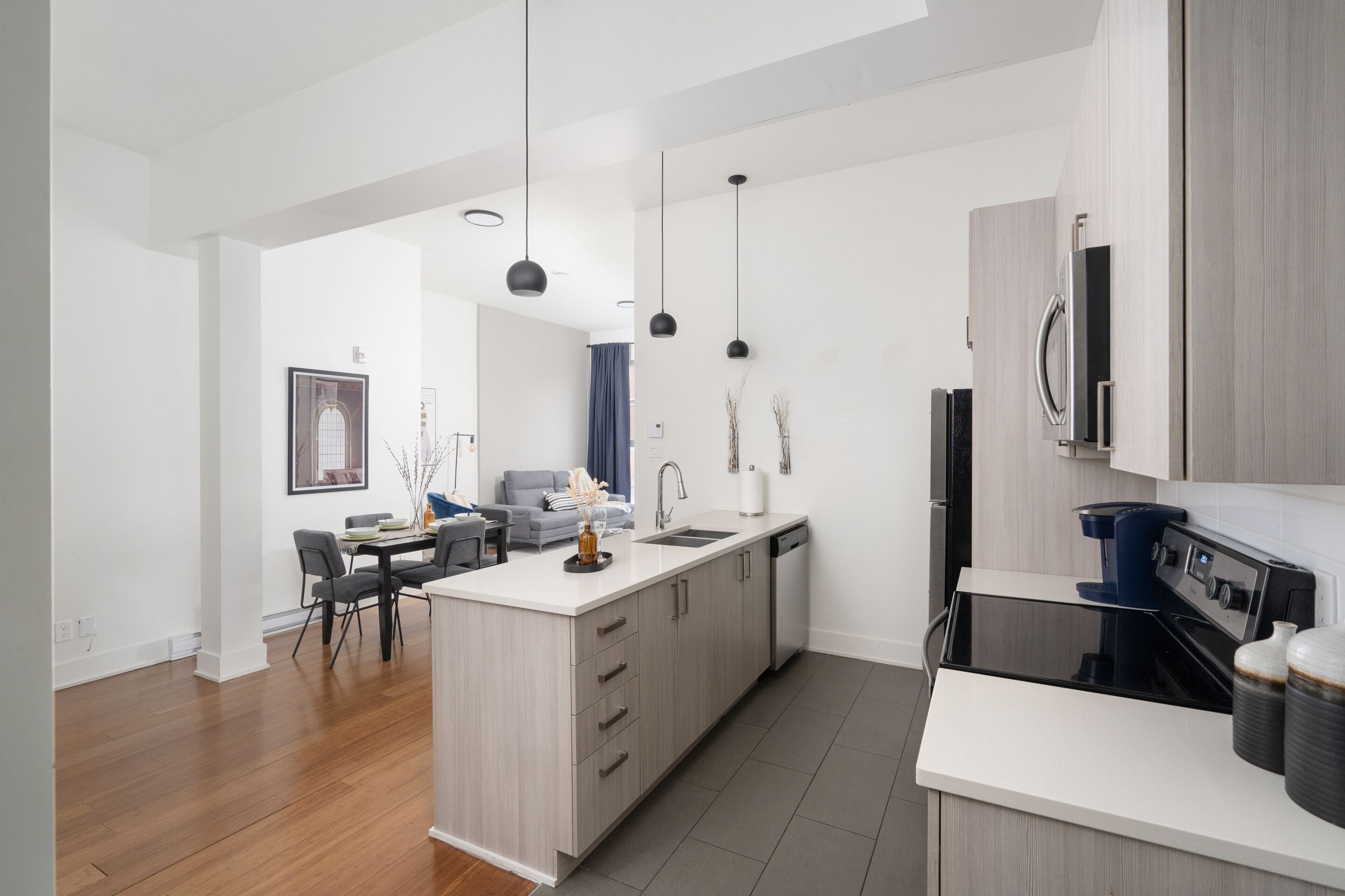 A modern kitchen with a central island, built-in appliances, and pendant lighting.