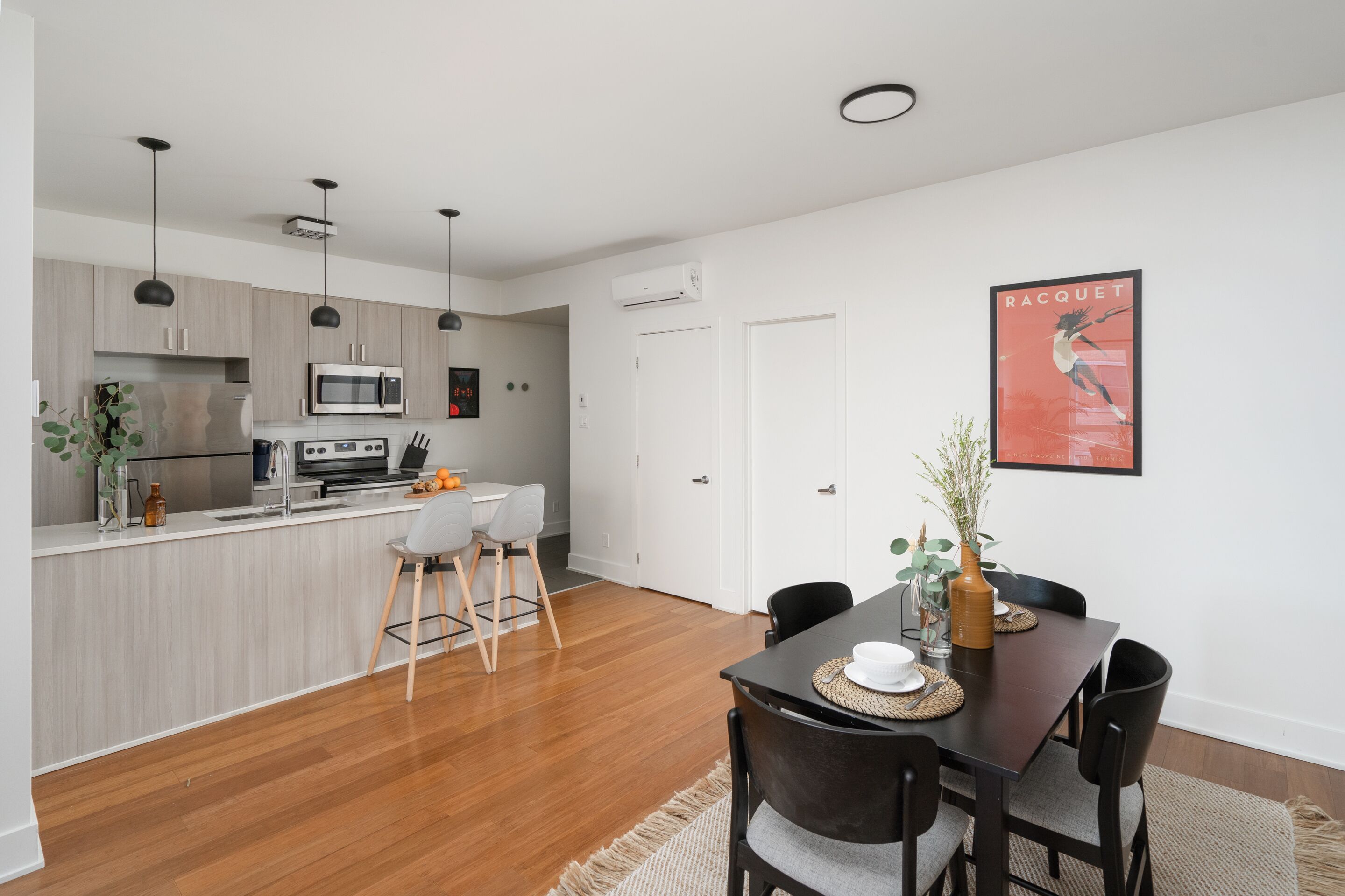 Cocina moderna con microondas, estufa y lavabo.  Hay un comedor con mesa y sillas.