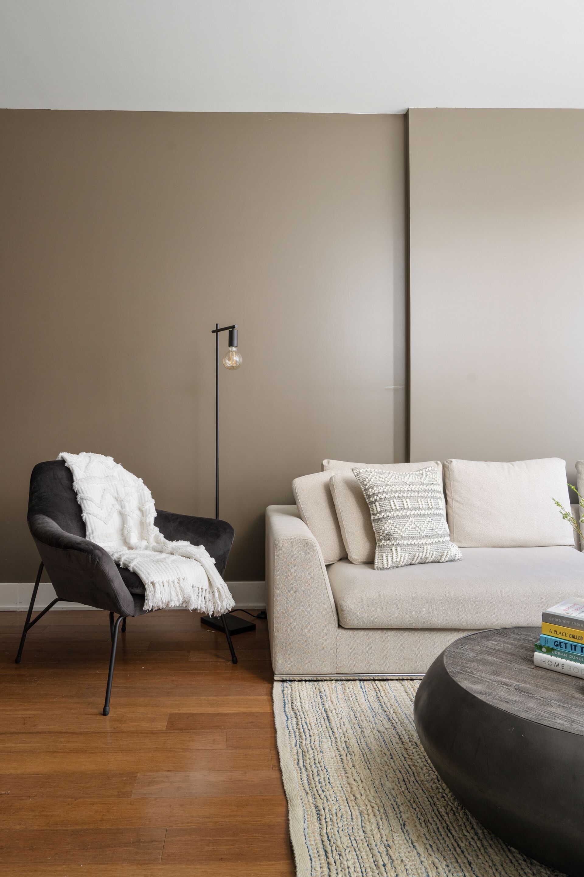 Ein modernes Wohnzimmer mit einer Couch, einem Sessel, einem Couchtisch und einer Stehlampe.