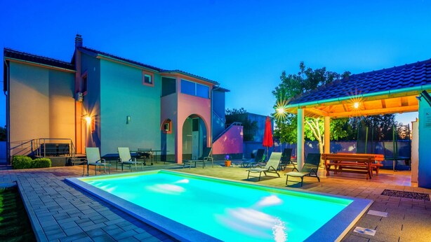 Ein Pool mit Liegestühlen und einem überdachten Sitzbereich.