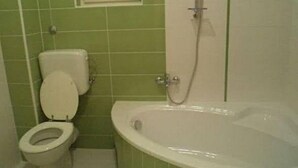 Ein Badezimmer mit Toilette, Badewanne und einem Fenster über der Toilette.