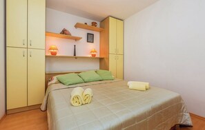 A bedroom with a bed, green pillows, a bedside table with a lamp, and a wardrobe. - Apartments Paola - Studio Apartment with Terrace and Sea View (Karlobag)