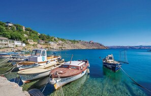Una marina amb diversos vaixells amarrats, aigua blava cristal·lina i un turó ple d'edificis.