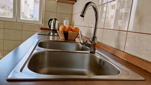 A kitchen with a stainless steel sink, a kettle, and a fruit bowl. - Apartment Neon - One Bedroom Apartment with Balcony (Zadar)