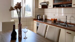 A modern kitchen with white cabinets, a stainless steel sink, and a window with a view of greenery. - Apartment Neon - One Bedroom Apartment with Balcony (Zadar)
