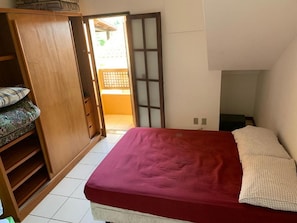 Quarto com cama, guarda-roupa e porta de correr para área externa.