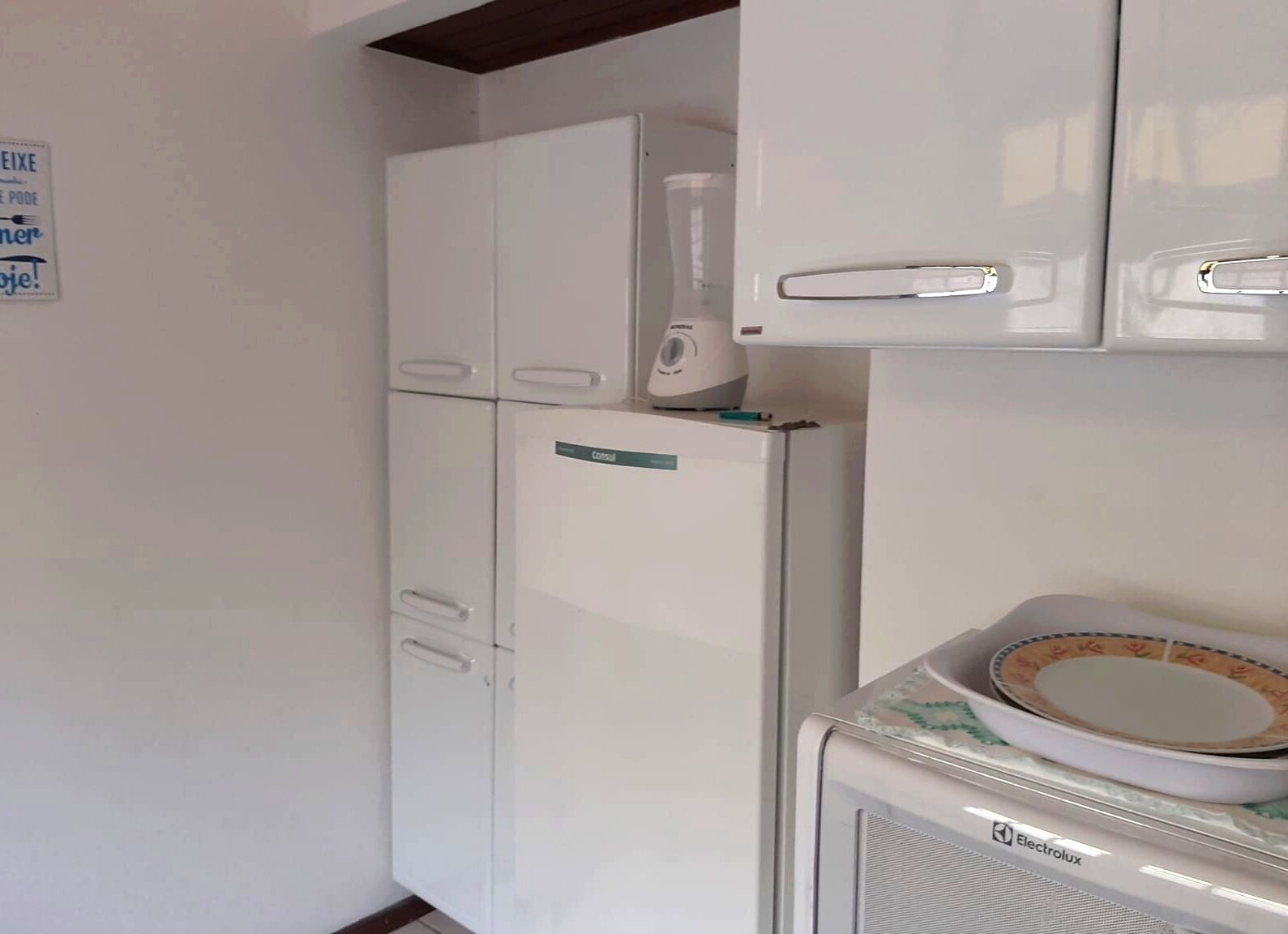 A compact kitchen with white appliances, including a refrigerator, microwave, and an Electrolux oven.