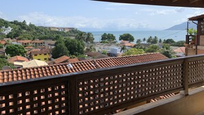 Un balcón con vistas a un pueblo costero, con tejados de teja y baranda de madera.