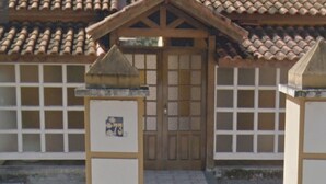 Un edificio tradicional con una puerta de madera, techo de tejas y una pequeña estructura que recuerda a un santuario en su parte frontal.