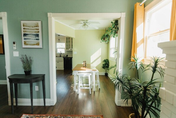 A spacious living area with a wooden floor, a dining table, and a kitchen in the background.