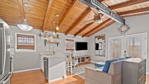 A spacious kitchen with a central island, wooden ceiling beams, and a dining area with a wicker sofa. - Seaside Serenity (Panama City Beach)