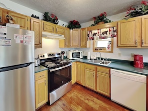 A kitchen with wooden cabinets, a stainless steel refrigerator, a stove, a microwave, a sink, and a dishwasher. - Black Bear Retreat by Taylor Made Deep Creek (McHenry)