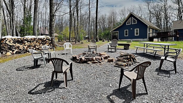 A rustic outdoor seating area with a fire pit, picnic table, and chairs. - Black Bear Retreat by Taylor Made Deep Creek (McHenry)